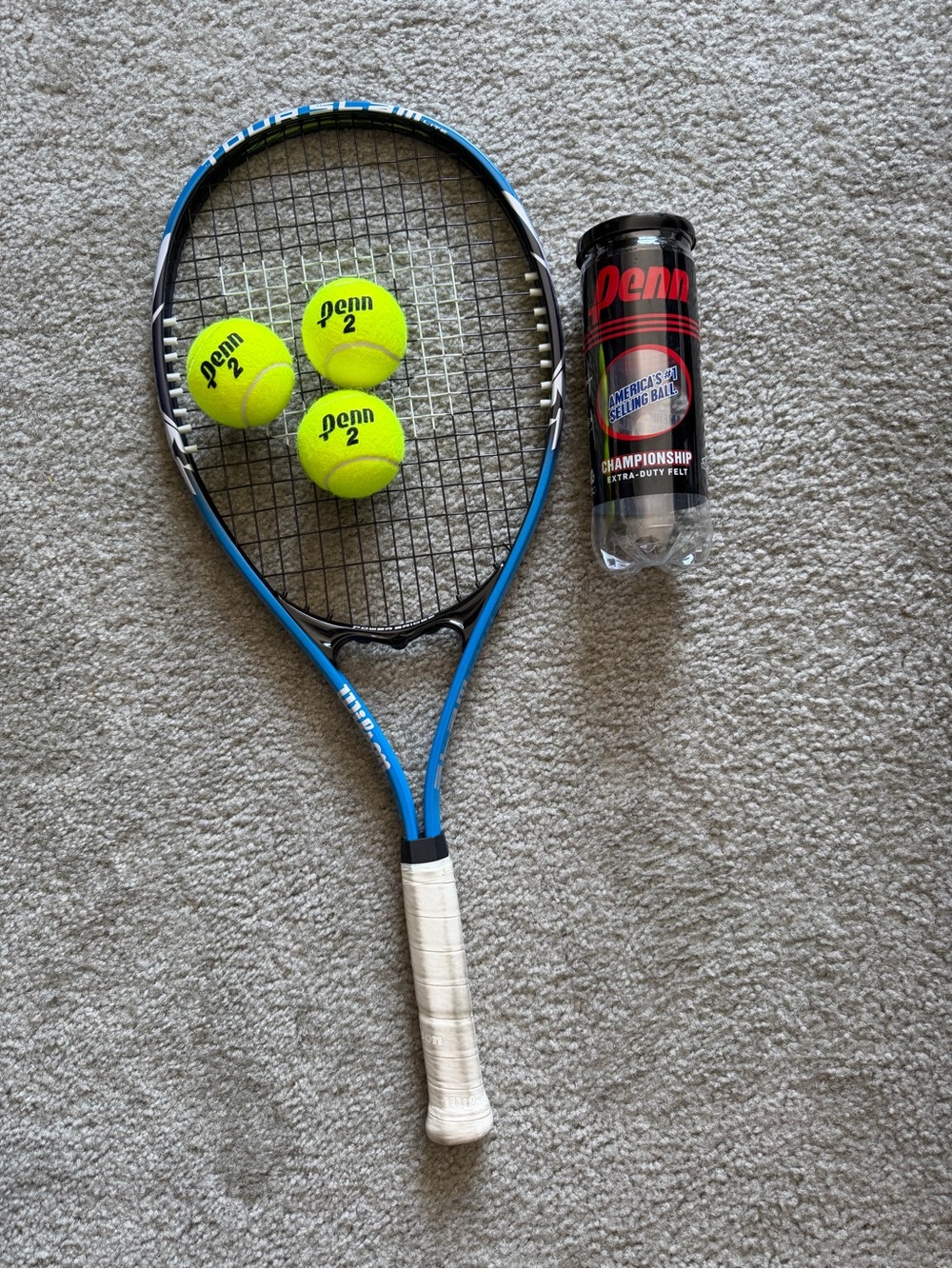Wilson blue and black tennis racket with neon yellow Penn balls